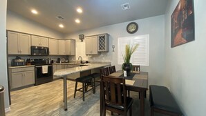 Una cocina moderna con una isla central, electrodomésticos de acero inoxidable y un comedor con sillas y mesa de madera.