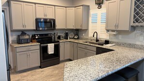 Una cocina moderna con encimeras de granito, electrodomésticos de acero inoxidable y armarios de color gris claro.
