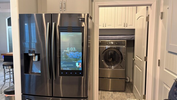 Un refrigerador de acero inoxidable con pantalla digital, dispensador de agua integrado y un microondas.