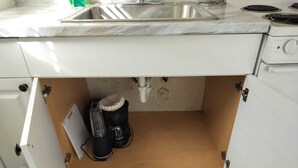 Una cocina con un lavamanos, una cafetera y un mueble bajo la encimera.