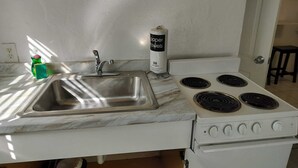 Una cocina con un lavamanos, estufa y una botella de toallas de papel.
