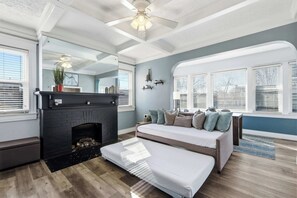 Ein modernes Wohnzimmer mit Kamin, einer Couch und einem großen Fenster mit Jalousien.
