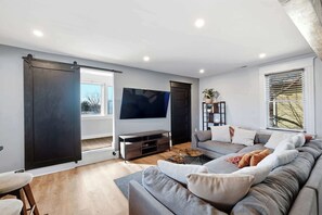 Ein modernes Wohnzimmer mit einem grauen Sofa, einem Couchtisch und einem Flachbildfernseher.