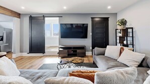 A modern living room with a grey sofa, a coffee table, a TV, and a sliding door leading to a balcony.