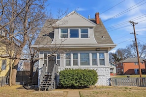 A two-story house with a front porch, a staircase, and a green bush in front. - Elegant Historic Apartment with Craftsman Details (Louisville)