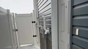 A narrow, snow-covered pathway between buildings with exterior walls and doors. - Alake Villa (Saskatoon)
