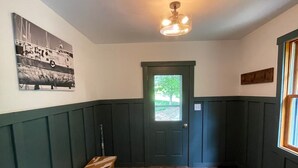Un couloir avec un banc, une porte, un tapis à motifs et un tableau accroché au mur.