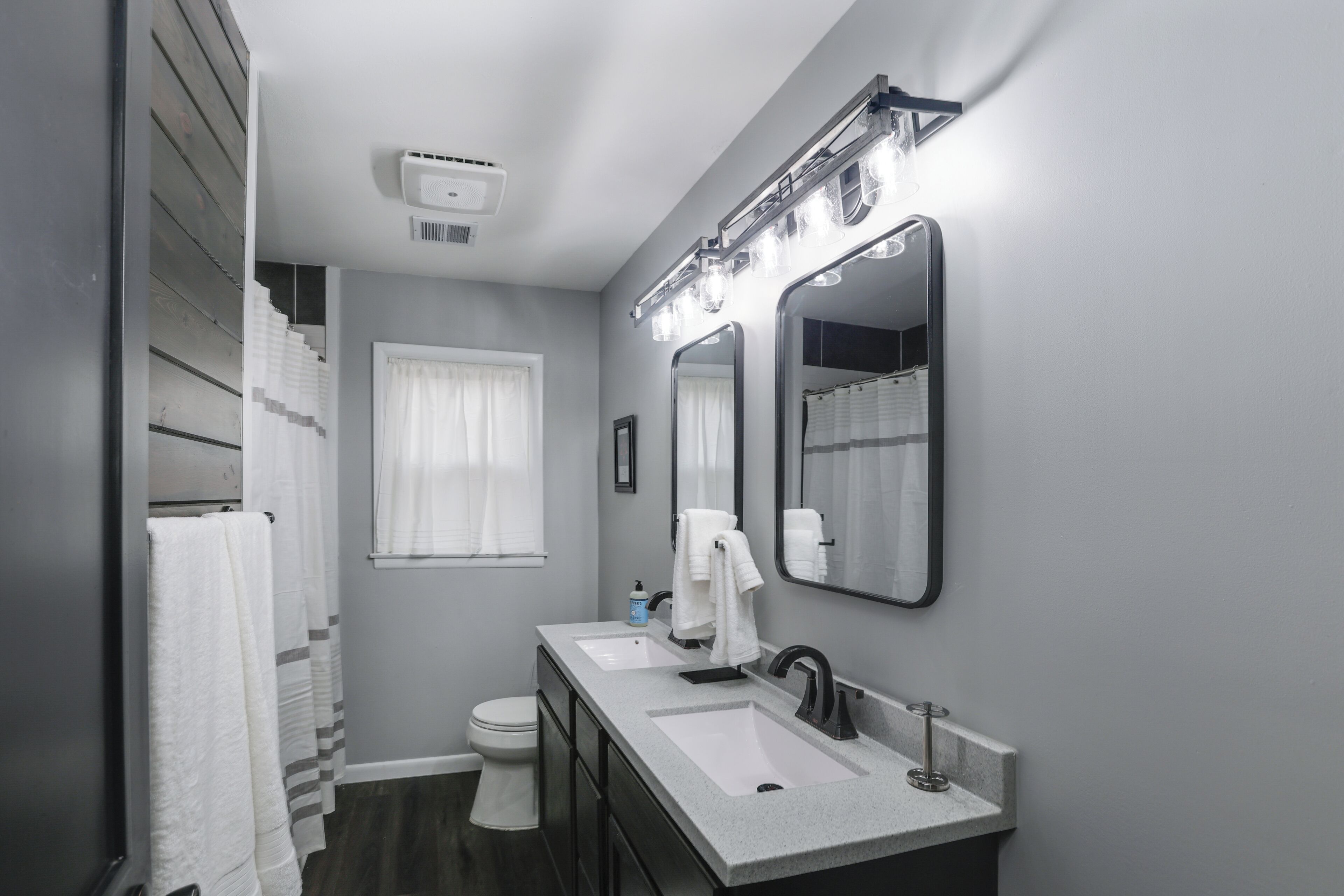 Une salle de bain moderne avec deux lavabos, un grand miroir et un espace douche.