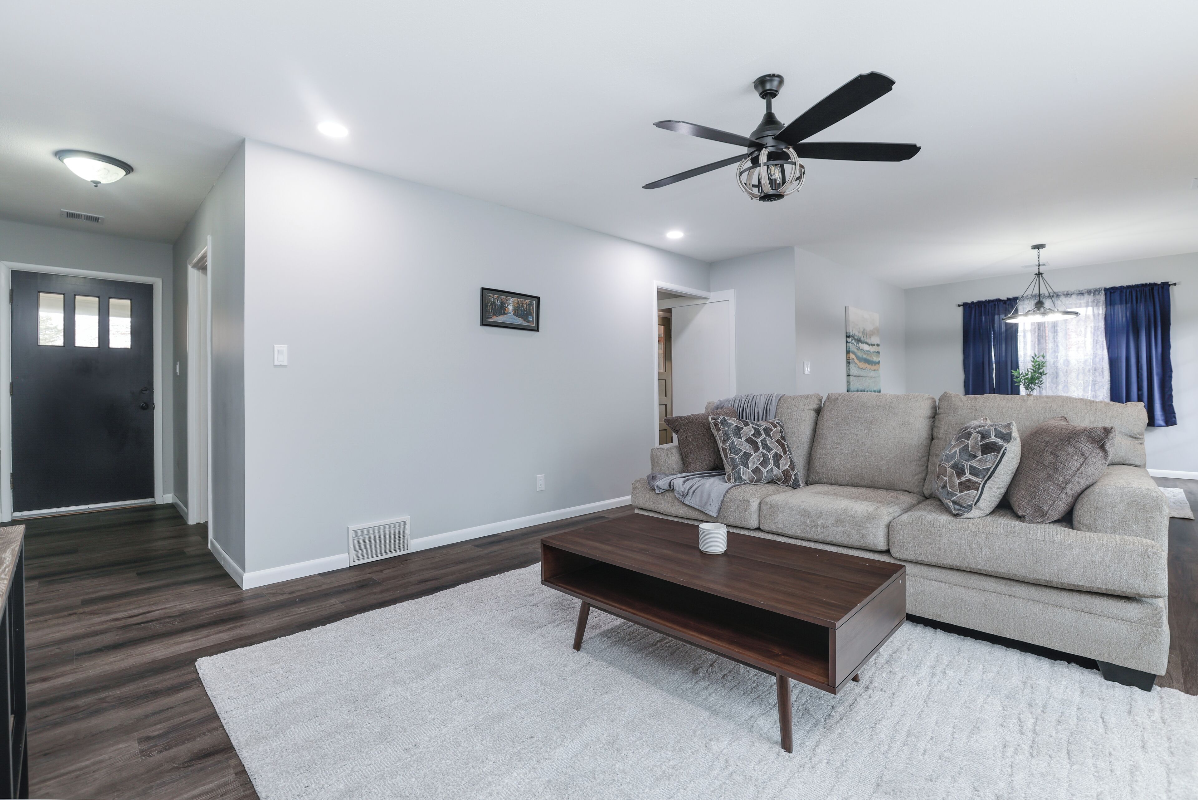 A modern living room with a sofa, coffee table, and ceiling fan.