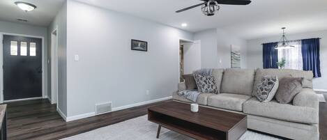 A modern living room with a sofa, coffee table, and ceiling fan.