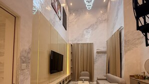 Un salon moderne doté d’un grand téléviseur à écran plat, d’un canapé, d’une table basse et d’un luminaire décoratif au plafond.
