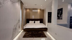 Une chambre moderne dotée d’un grand lit, de murs en marbre, d’un éclairage encastré et d’un appareil de climatisation.