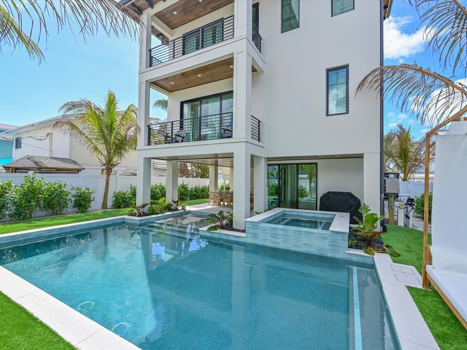 A modern two-story house with a swimming pool, outdoor seating, and a covered patio area.