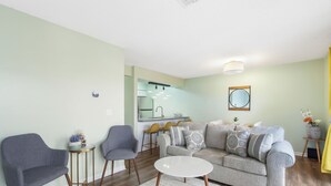 A living room with a grey sofa, two armchairs, a white coffee table, and a kitchen in the background. - Stylish Branson Retreat with Golf and Amenities (Branson)