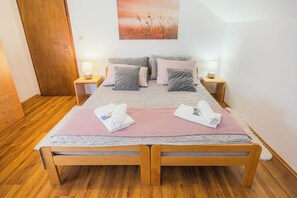 A double bed with a quilted mattress, two bedside tables with lamps, and a wooden door.
