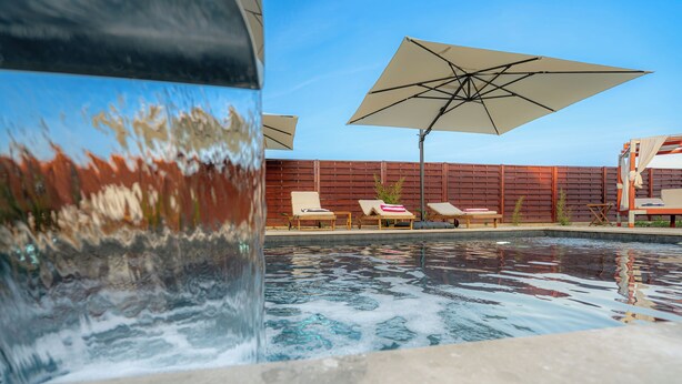 A swimming pool with lounge chairs and umbrellas, surrounded by a wooden fence. - Slavonian home with pool, jacuzzi, barbecue and family fun (Požega)