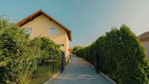 A residential building with a sloped roof, a gravel driveway, and a metal fence. - Slavonian home with pool, jacuzzi, barbecue and family fun (Požega)