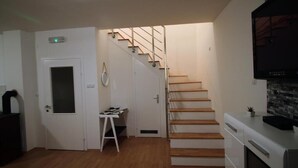 Una cocina compacta con una escalera de madera que sube a un segundo piso.