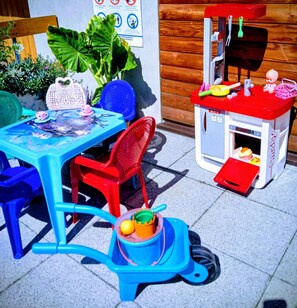Ein Spielbereich für Kinder mit einem Tisch, Stühlen, einer Spielküche und einem Spielzeugauto.