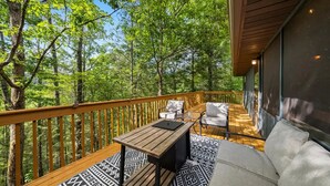 A deck with a wooden railing, a table, two chairs, and a sofa. - Little Toasty / 9 min to Dollywood! 8 min to Pkwy! (Pigeon Forge)