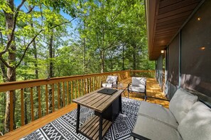 Eine Terrasse mit Holzgeländer, einem Tisch, zwei Stühlen und einer Couch.