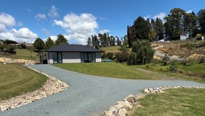 A modern house with a gravel driveway leading to a white building with large windows. - Private attractive single story bungalow, sleeping 4 people. (Redwood Valley)