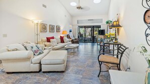 A spacious living room with a sectional sofa, a coffee table, and a dining area with a table and chairs. - Monthly Coastal Retreat | Garage, Pools, Beach Access & Quiet Community (New Smyrna Beach)
