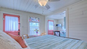 A bedroom with a bed, a desk, and a kitchenette.