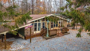 Une cabane avec une façade en pierre, une terrasse en bois et un drapeau américain.