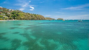 Eine Küstenlandschaft mit klarem türkisblauem Wasser, Booten und einer Hügelsiedlung mit Gebäuden.