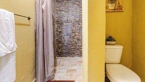 A bathroom with a shower curtain, a toilet, and a tiled wall.