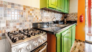 A kitchen with a gas stove, a sink, and green cabinets.