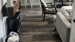 Een woonkamer met een bank, een televisie, een eettafel met stoelen en een open haard.