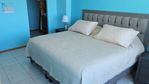 A neatly made bed with a tufted headboard, a bedside table with a lamp, and a nightstand with drawers. - 2-bedroom apartment in peaceful Mazatlán with an amazing front ocean view (Mazatlán)