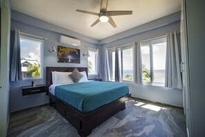 Ein Schlafzimmer mit einem Bett, einem Deckenventilator und Blick aufs Meer.