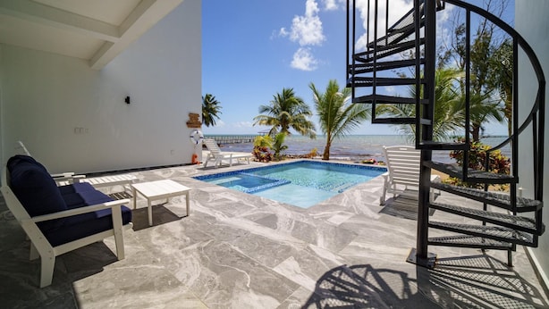 Ein Poolbereich mit Wendeltreppe, Liegestühlen und Blick auf den Ozean.