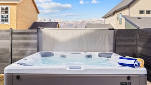 A hot tub in a backyard with a view of mountains in the background.