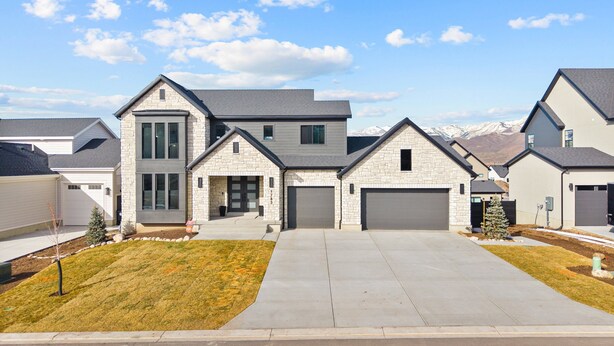 A modern two-story house with a stone facade, a garage, and a driveway leading to the entrance.