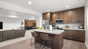 A modern kitchen with wooden cabinets, stainless steel appliances, and a central island with bar stools.