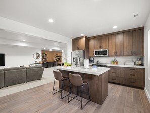 A modern kitchen with wooden cabinets, stainless steel appliances, and a central island with bar stools. - Modern Mountain Escape, Hot Tub, Deer Valley Close (Heber City)