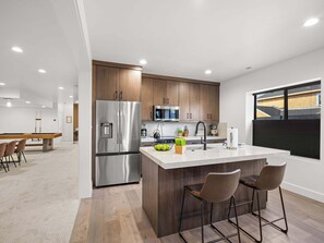 A modern kitchen with a stainless steel refrigerator, wooden cabinets, a marble countertop, and a large window. - Modern Mountain Escape, Hot Tub, Deer Valley Close (Heber City)