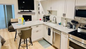 Una cocina moderna con armarios blancos, horno empotrado, microondas y un televisor de pantalla plana grande.