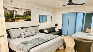 Un dormitorio con cama, escritorio, silla, armario y un cuadro en la pared.