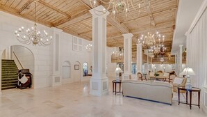 A spacious lobby with a grand staircase, chandeliers, and a seating area with a sofa and tables. - Palm Breeze Palm Beach Island Studio Heated Pool (Palm Beach)