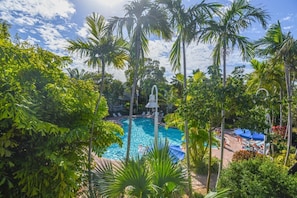 Ein Swimmingpool, umgeben von Palmen und Liegestühlen.