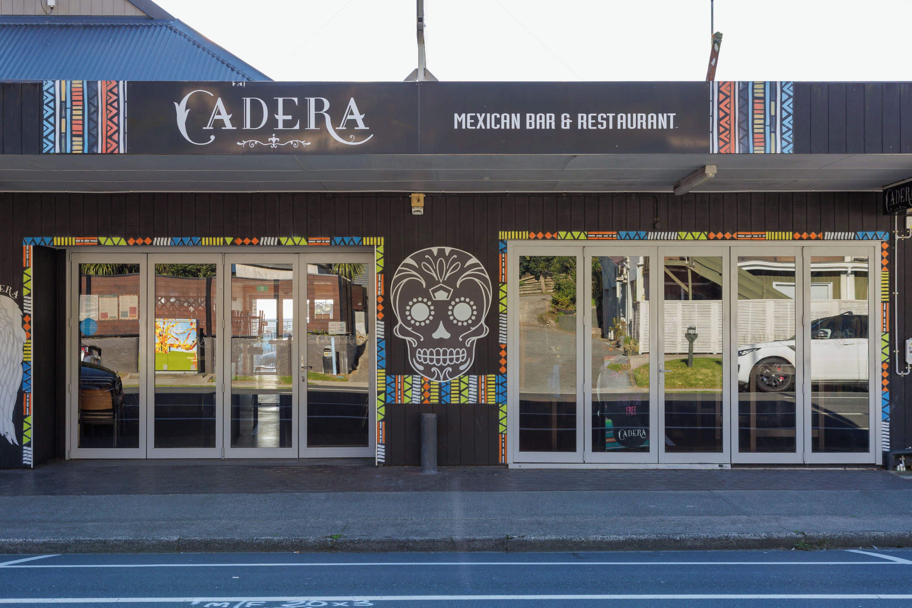 A Mexican bar and restaurant named 'CADERA' with a large skull decoration and colorful patterns on the facade.