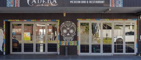 A Mexican bar and restaurant named 'CADERA' with a large skull decoration and colorful patterns on the facade.