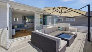 Una zona relax esterna coperta, con un divano, un tavolino da caffè e un tavolo da pranzo.