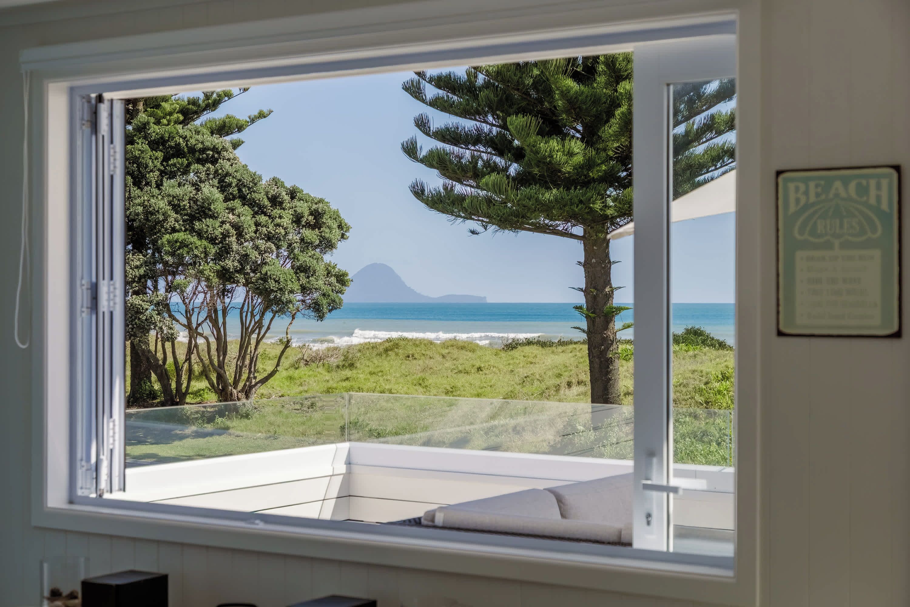 A room with a large window overlooking a beach and ocean.