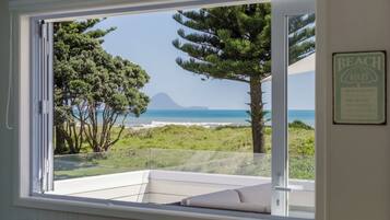 A room with a large window overlooking a beach and ocean.
